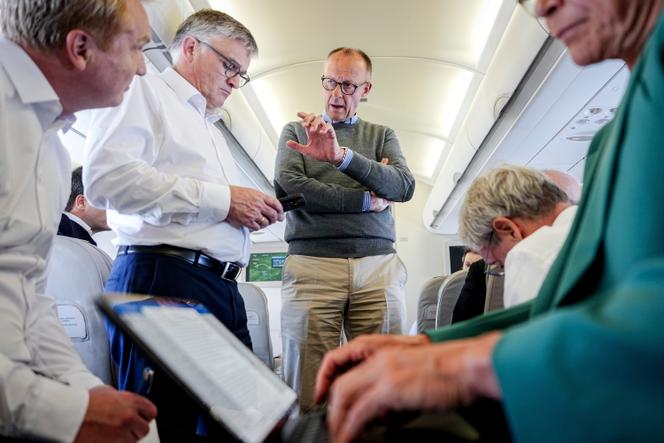 Le chancelier allemand Friedrich Merz (au centre) s’entretient avec des journalistes à bord de l’Airbus A319 de l’armée de l’air à destination de Washington, le 18 août 2025.
