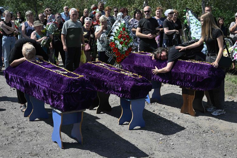 Parents et amis pleurent devant les cercueils lors des funérailles de Mykyta et Sofia Lamekhov et de leur fils Lev au cimetière de Sloviansk, le 5 août 2025, en pleine invasion russe de l’Ukraine.