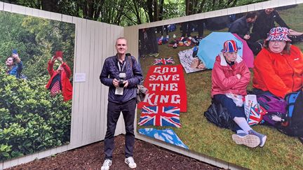 Le photographe Peter Dench devant deux de ses photos exposées à La Gacilly. (ANNE CHEPEAU / FRANCEINFO / RADIO FRANCE)