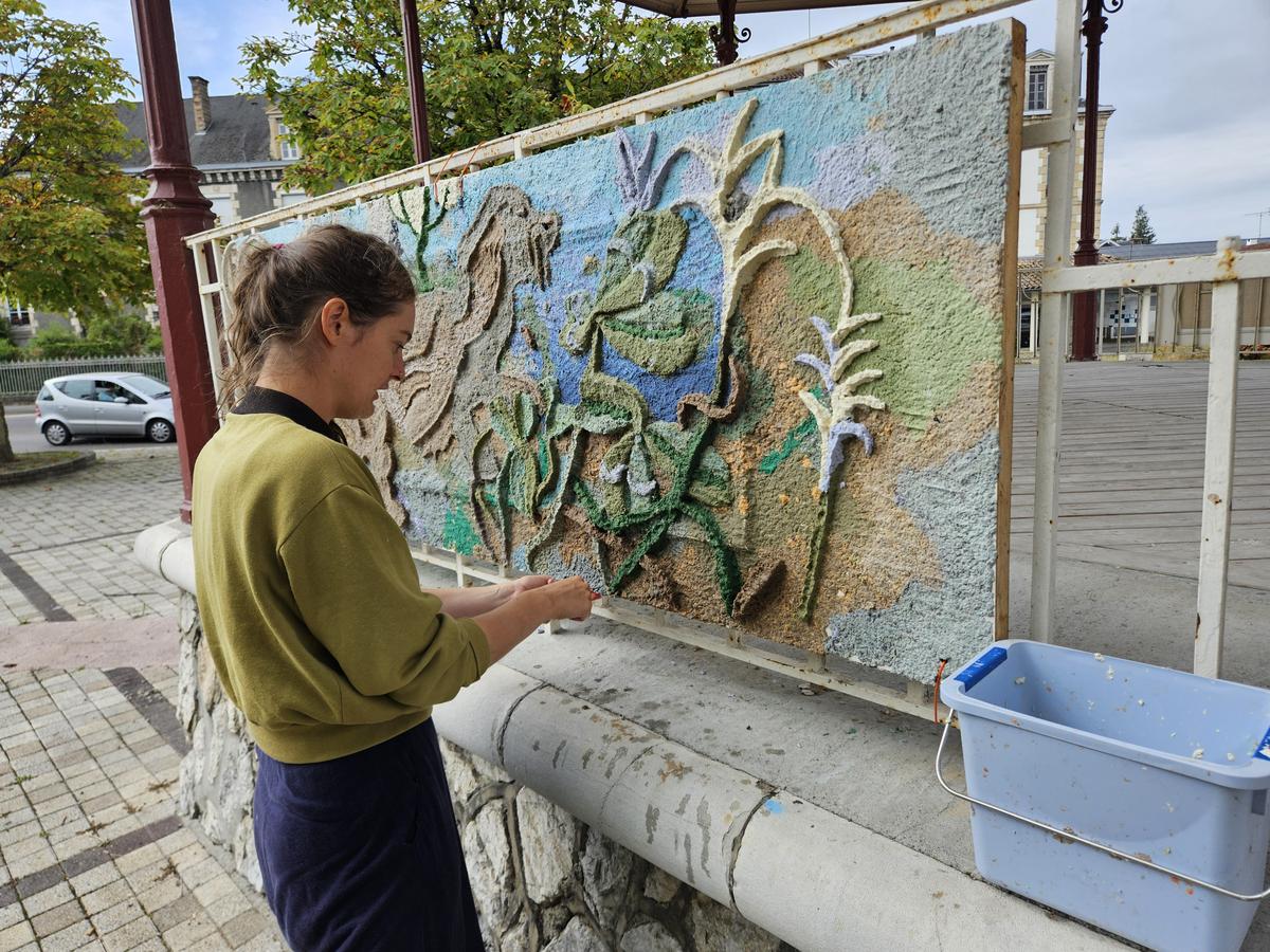L’artiste Zélie Boulestreau explique qu’il faut appliquer la pâte à papier avec précision.
