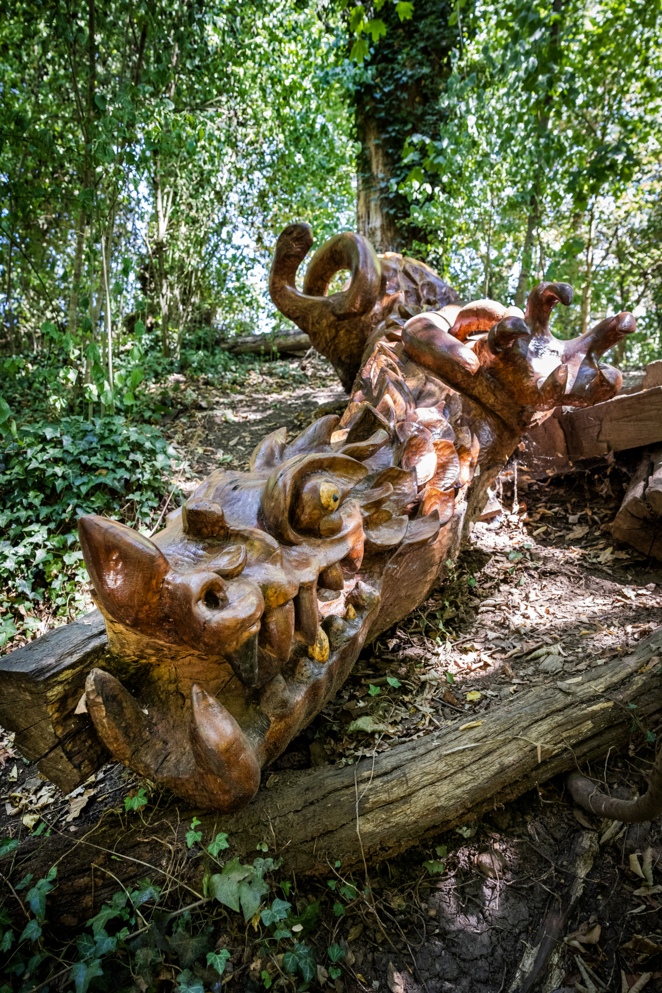Sculpture en bois de Jacques Baume, située dans la campagne Masset à Saint-Jean, entourée de végétation.