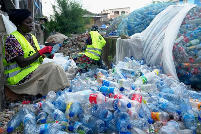 Des ouvriers utilisent des lames de rasoir pour gratter les étiquettes de différentes bouteilles en plastique de boissons gazeuses à la Street Waste Company, à Lagos, au Nigeria, le lundi 11 août 2025.