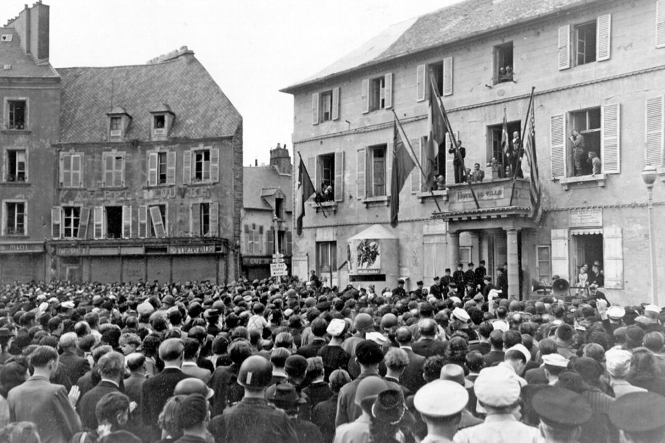 Le 20 août 44, le Général de Gaulle fait un discours devant les habitants de Cherbourg rassemblés devant l'Hôtel de ville.
A gauche sur la façade un petit abri bétonné de défense rapprochée avec  un créneau d'observation , il est recouvert d'une affiche de propagande alliée.
Voir l'affiche ici : http://www.flickr.com/photos/mlq/1568608387/in/pool-autresphotosnormandie/
Dans le fond à gauche un panneau :
N 13
N 801
ONE WAY TRAFFIC
En français : sens unique
voir la p001029 même endroit le 27 juin 1944:
http://www.flickr.com/search/?w=58897785@N00&q=p001029
voir la p012730 et 2GM_CHBG109 :
http://www.flickr.com/search/?w=58897785%40N00&q=2GM_CHBG109+or+p012730+or+p011755&m=text
Deux films:
http://www.criticalpast.com/video/65675054754_General-Charles-De-Gaulle_crowd-greets-General_US-flag-on-balcony_people-on-road
http://www.criticalpast.com/video/65675054753_General-Charles-De-Gaulle_woman-with-flowers_flags-on-balcony_General-amidst-crowd
De nos jours:
http://www.flickr.com/photos/mlq/5029297102/
Voir également une plaque sur la façade à droite de l'entrée:
http://www.flickr.com/photos/mlq/5579356963/ - p011755