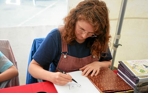 Anne Montel, autrice d’album jeunesse, dédicace les pages de ses ouvrages avec des illustrations personnalisées.