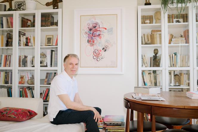Christian Berst, galeriste spécialisé en art brut, avec une œuvre de Lubos Plny accrochée au mur, dans son appartement, à Paris, le 1ᵉʳ juillet 2025.