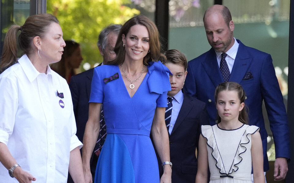 Kate, le prince George, le prince William et la princesse Charlotte sont accueillis par Sally Ambrose (à gauche), membre du comité de gestion des championnats, à leur arrivée au tournoi de Wimbledon, le 13 juillet 2025.
