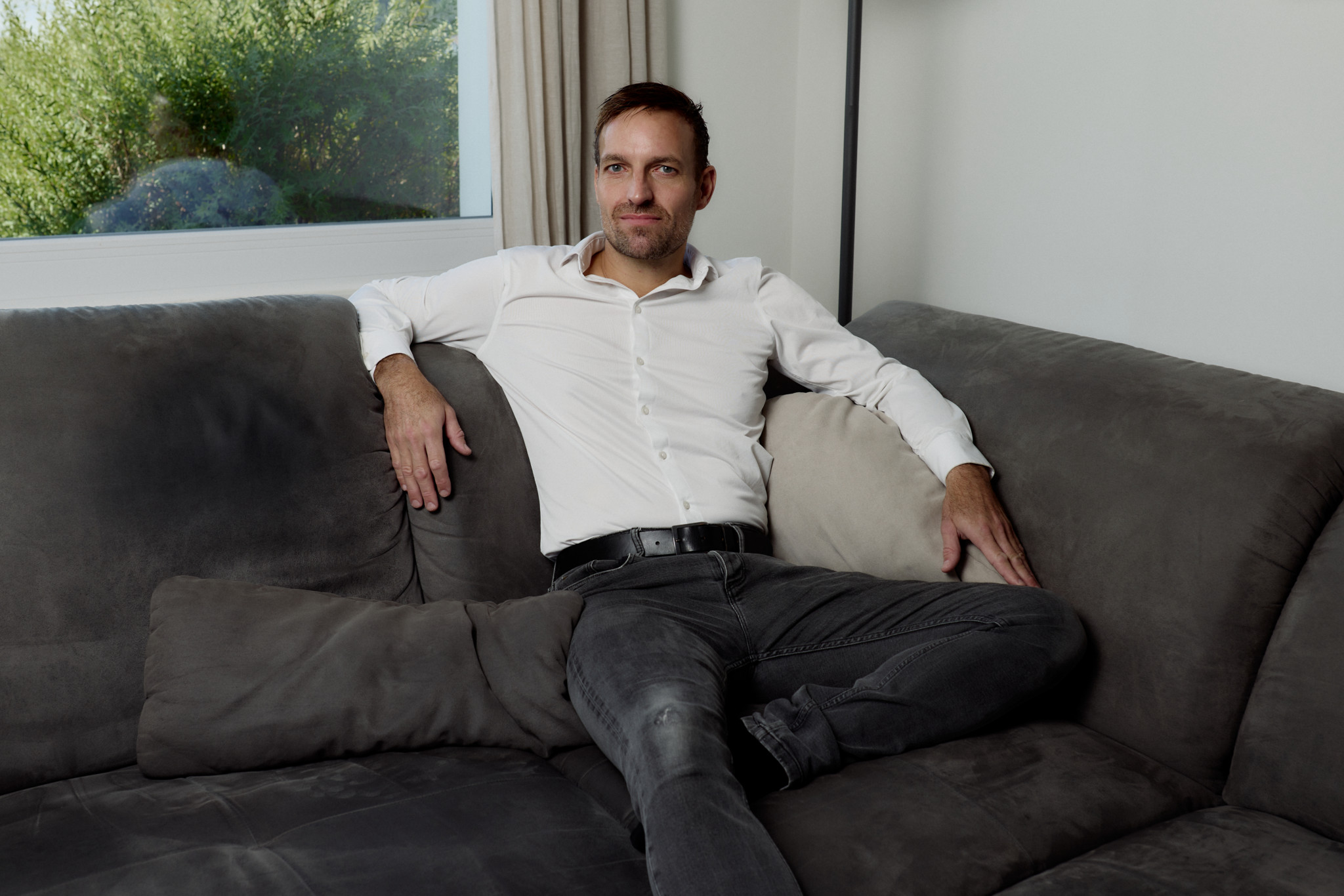 Christoph Anderegg, patient atteint de longue COVID, teste un patch de nicotine, assis sur son canapé chez lui à Herisau.
