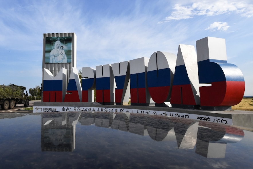 Un camion militaire russe passe devant les lettres géantes formant le mot Marioupol, peintes aux couleurs de la Russie, le 17 juillet 2025 dans la ville ukrainienne de Marioupol contrôlée par la Russie