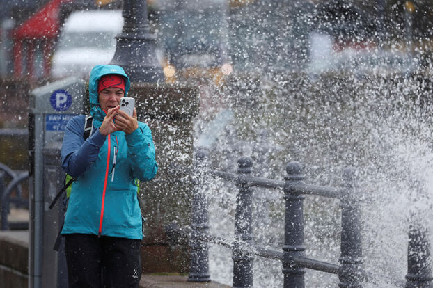 Dans la ville d’Oban, une femme prend des photos avec son téléphone sur l’esplanade. Reuters/Russell Cheyne