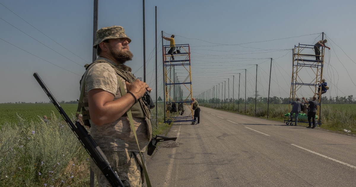 Un soldat ukrainien monte la garde tandis que d'autres soldats installent des filets anti-drone dans la région de Donetsk, le 8 juillet 2025.