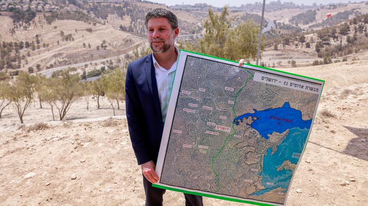Le ministre israélien des Finances d’extrême droite, Bezalel Smotrich, tenant une carte d’une zone proche de la colonie de Ma’Ale Adumim, un corridor terrestre connu sous le nom de E1, à l’extérieur de Jérusalem, en Cisjordanie occupée, le 14 août 2025.