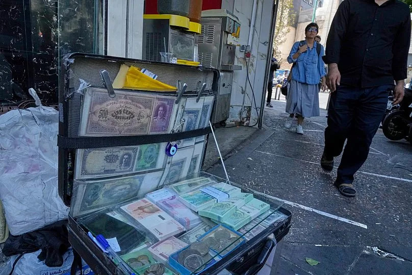 Des billets de banque iraniens actuels et d'avant la révolution sont exposés par un changeur de monnaie dans une rue du centre-ville de Téhéran, le 28 août 2025.