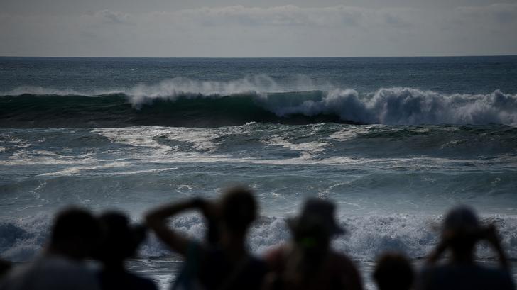 Des gens regardent les grosses vagues, provoquées par une houle cyclonique causée par l’ancien ouragan Erin et des coefficients de marée élevés, sur la plage de Lacanau, le 26 août 2025.