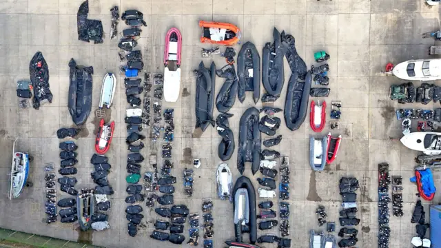 Vue d'en haut de petits bateaux et de moteurs hors-bord dans divers états de délabrement utilisés par des personnes considérées comme des migrants pour traverser la Manche dans un entrepôt à Douvres, dans le Kent.