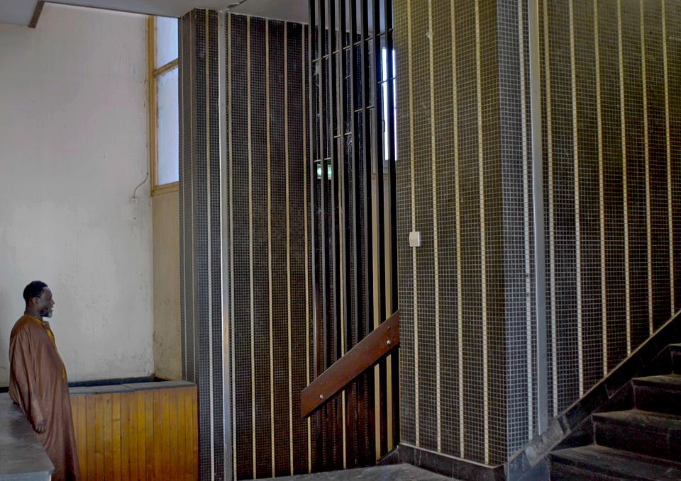 Un homme en habit traditionnel au pied d'un escalier. 