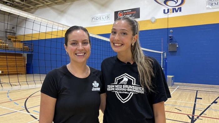 Les deux personnes souriantes devant un filet de volleyball. 