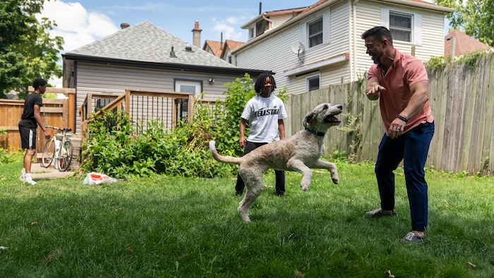 Joshua Lawrence joue avec son chien et son beau-fils dans sa cour arrière.