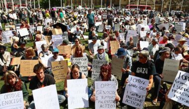 Des manifestants assis au sol avec des pancartes où on peut lire des slogans sympathisants à la Palestine.