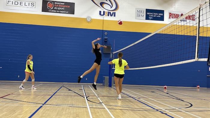 Jeune femme qui effectue une attaque devant un filet de volleyball.