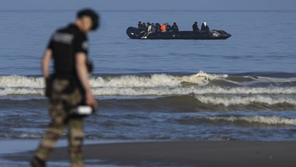 Un gendarme français face à un bateau transportant des exilés, à la plage d'Equihen, dans le Pas-de-Calais, le 30 juin 2025. (photo d'illustration) (SAMEER AL-DOUMY / AFP)