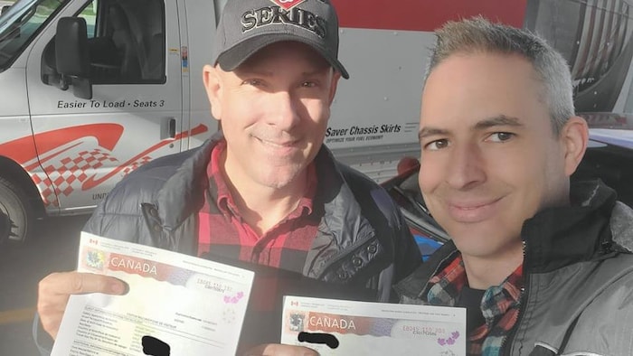 Un égoportrait de Robert Apgar-Taylor et de Robert Taylor montrant leurs documents d'immigration à leur arrivée au Canada.