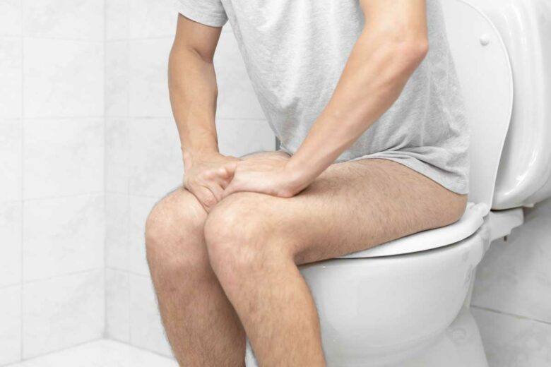 Un homme assis sur des toilettes.