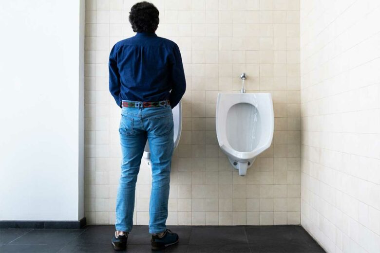 Un homme dans des urinoirs publics.