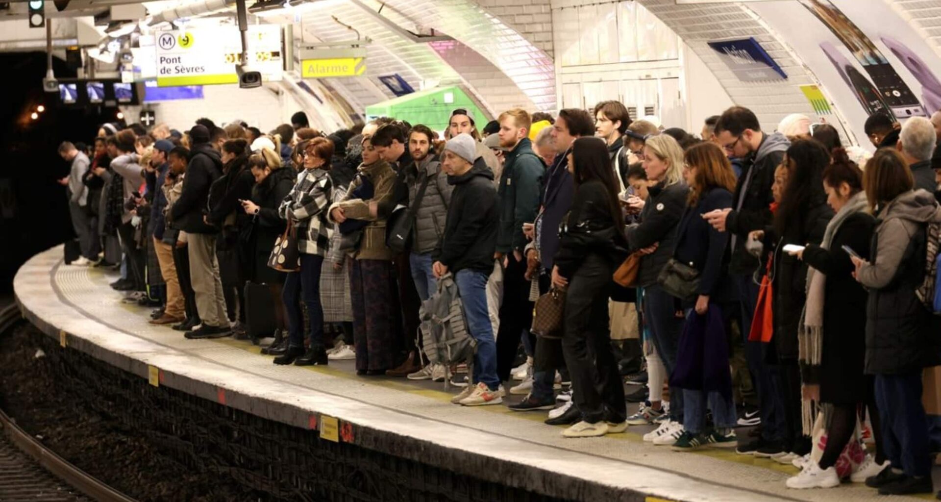 Une foule de voyageurs attend sur un quai de métro en Île-de-France, illustrant l'affluence et les perturbations dans les transports en commun.