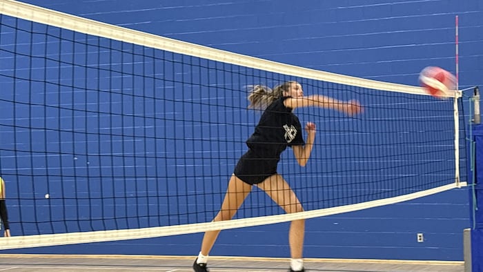 Jeune fille en noire qui fait une attaque au volley-ball