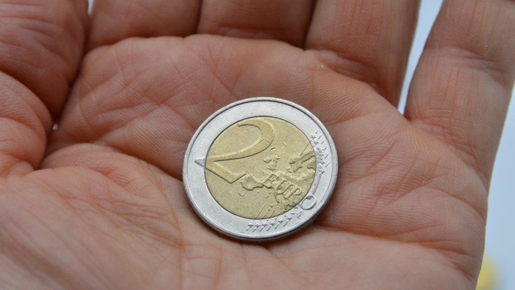 Main tenant une pièce de deux euros.