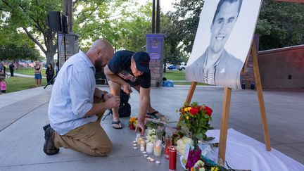 Des Américains déposent des fleurs et des bougies devant un portrait de l'influenceur américain Charlie Kirk, tué d'une balle, le 10 septembre 2025. (MELISSA MAJCHRZAK / AFP)