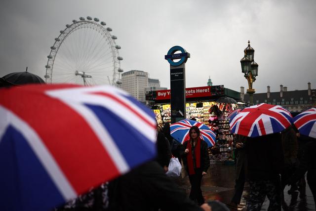 Des touristes se protègent de la pluie devant le pont de Westminster, à Londres, au Royaume-Uni, le 10 mars 2024.