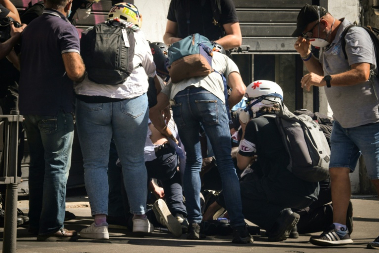 Un journaliste blessé de France TV (au centre en bas) est examiné par des secouristes lors de manifestations à Lyon, le 18 septembre 2025 ( AFP / OLIVIER CHASSIGNOLE )