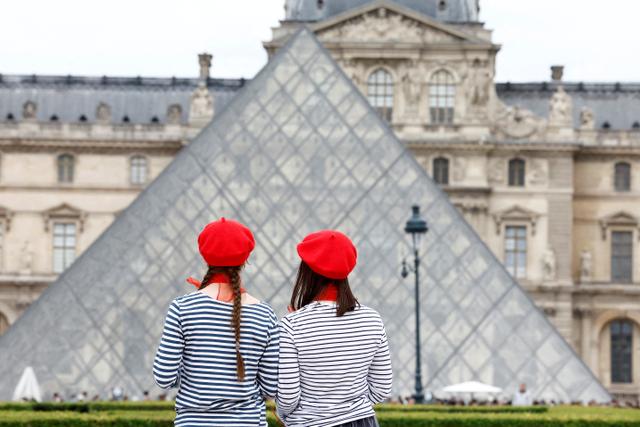 Des touristes portant des bérets rouges et des marinières devant la pyramide du Louvre à Paris, le 5 mai 2025. 