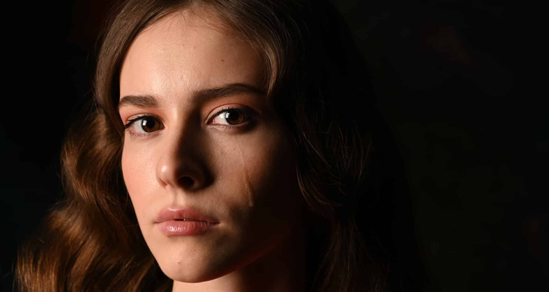Close Up Portrait Of Woman Crying Against Black Background
