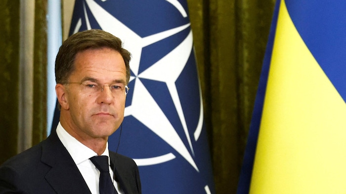 Mark Rutte debout devant les drapeaux de l'OTAN et de l'Ukraine.