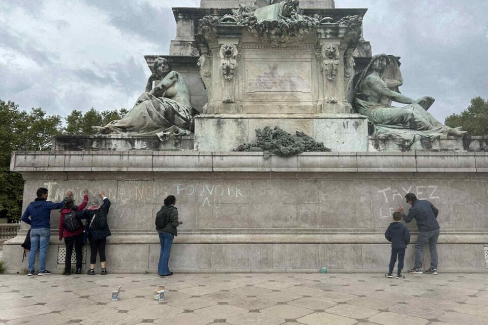 Quelques personnes écrivent à la craie sur le monument des Girondins, place des Quinconces à Bordeaux.