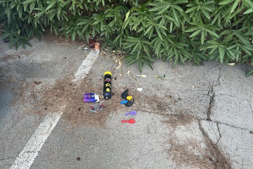 Une bonbonne de protoxyde d'azote vide, des embouts et des ballons jetés sur un parking privé