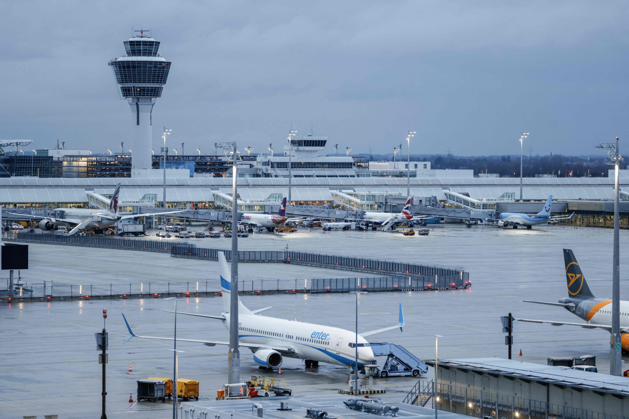 Vue générale de l’aéroport international de Munich avec plusieurs avions stationnés sur le tarmac, sous un ciel nuageux, en février 2024.