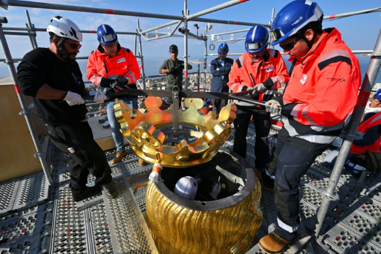 Des ouvriers remettent en place la couronne dorée de la statue de la Bonne Mère, à Marseille, le 17 octobre 2025 ( AFP / Christophe SIMON )