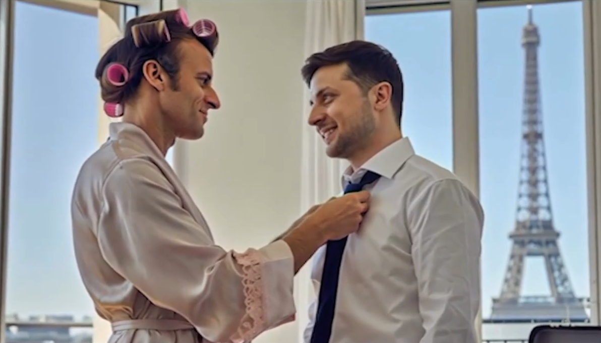 Deux hommes, l’un en robe de chambre avec des bigoudis, l’autre en chemise et cravate, souriants à Paris avec la Tour Eiffel en arrière-plan. Émission satire russe Politukladchik.