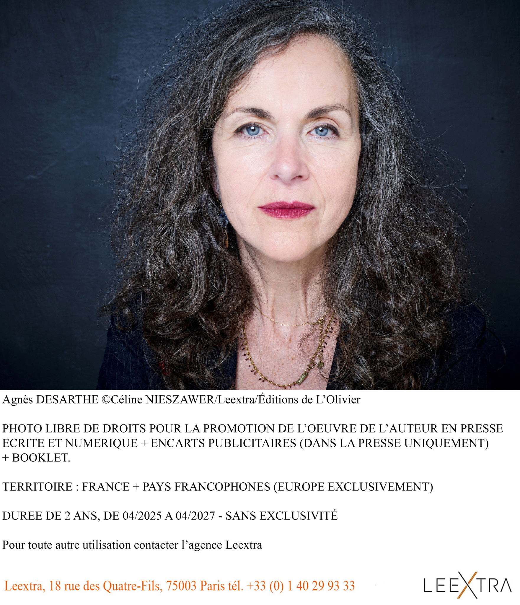 Portrait d’Agnès Desarthe, auteure, avec des cheveux bouclés et foncés, portant un pull noir sur un fond bleu foncé.