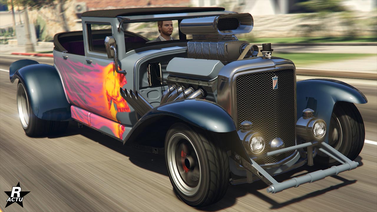 Image présentant la voiture d'halloween Albany Fränken Stange vue de devant dans le jeu vidéo GTA Online. Il s'agit d'un hot road d'un véhicule ancien modifié. La voiture ne dispose pas de capot et le moteur imposant est clairement visible. Des pots d'échappement sortent du moteur et les côtés latéraux disposent d'une décalcomanie d'une tête de mort jaune et rouge qui a une traînée de flammes.