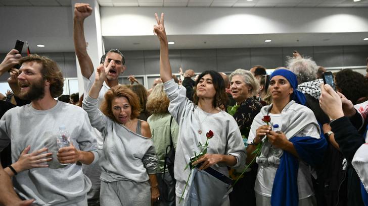 Rima Hassan (au centre avec une rose à la main) aux côtés de militants embarqués à bord de la flottille humanitaire à destination de Gaza. Ils sont ici accueillis par une foule de sympathisants, dans la zone des arrivées de l’aéroport international d’Athènes en Grèce, le 6 octobre 2025.