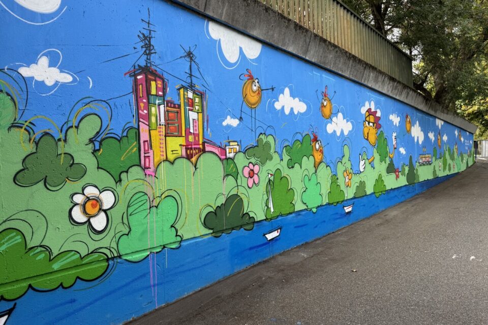 Des maisons, des poulets, le canal et des couleurs vives sont à retrouver sur la fresque. 