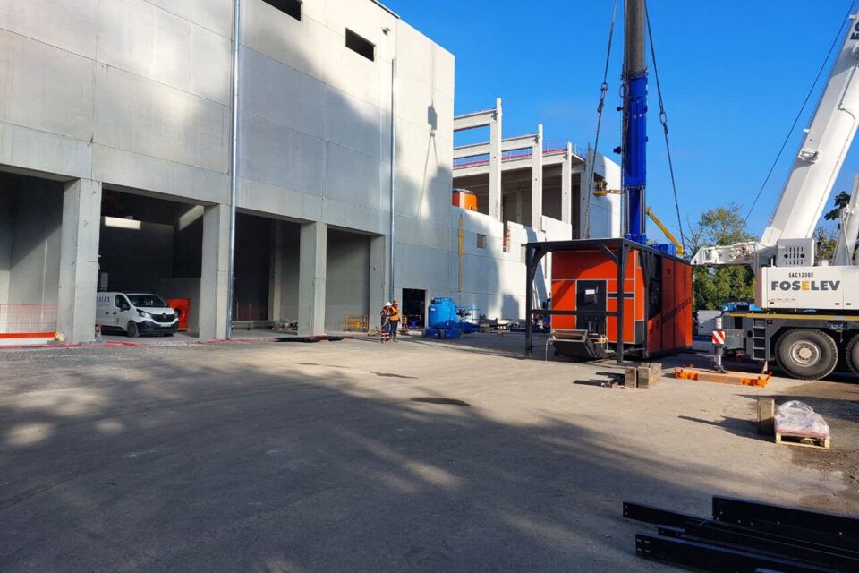 Une chaudière à biomasse (en rouge), en cours d'installation dans le nouveau bâtiment de la centrale encore en travaux.