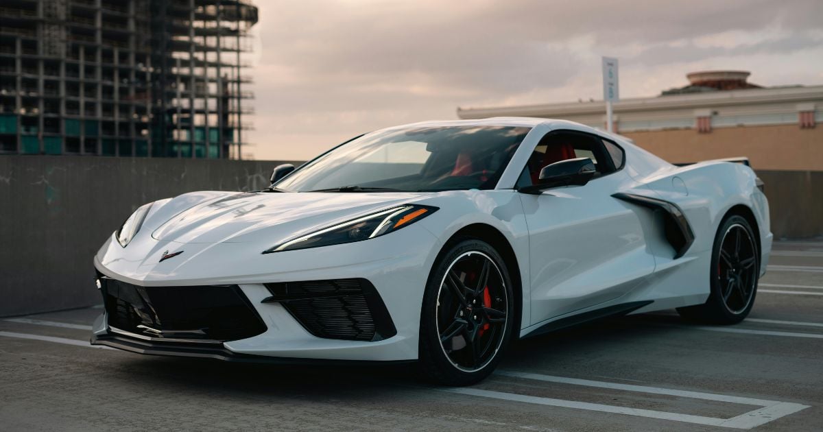 Trois oursons s'amusent avec une Corvette C8 devant une maison
