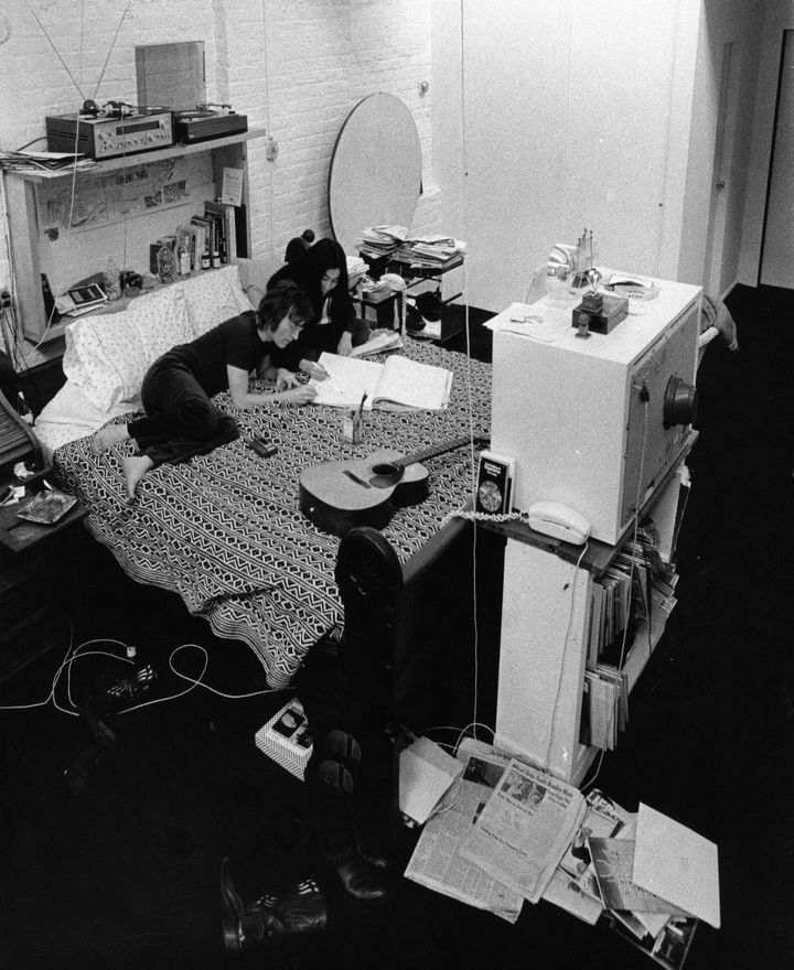 John Lennon et Yoko Ono, sur leur lit face à la télévision allumée en continu, dans leur appartement new-yorkais, au début des années 1970. (BEN ROSS / COURTESY OF PIECE OF MAGIC ENTERTAINMENT FRANCE)