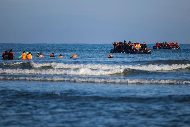 Des migrants s’avancent dans la mer pour tenter de monter à bord de bateaux afin de traverser la Manche, au large de la plage de Gravelines, dans le nord de la France, le 27 septembre 2025.