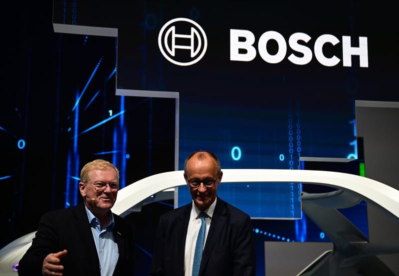 Le PDG de Bosch, Stefan Hartung (g) et le chancelier allemand lors de l'ouverture du Salon international de l'automobile IAA à Munich, le 9 septembre 2025 dans le sud de l'Allemagne